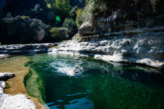 Man swimming in crystal clear natural rock pool river lagoon canyon