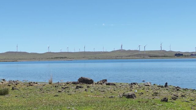 Scenic landscape of salt lake wetland and distant wind turbines in summer in Ulan Hada Volcano Geopark, Ulanqab, Inner Mongolia, China