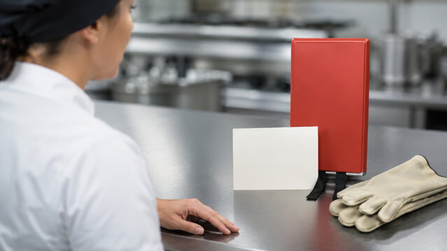 Emergency procedure flyer beside red folder and protective glove in commercial kitchen