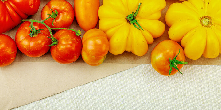 A vibrant flat lay of various homegrown heirloom tomatoes, including large ribbed, striped types