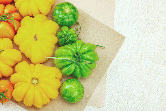 A vibrant flat lay of various homegrown heirloom tomatoes, including large ribbed, striped types