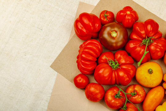A vibrant flat lay of various homegrown heirloom tomatoes, including large ribbed, striped types