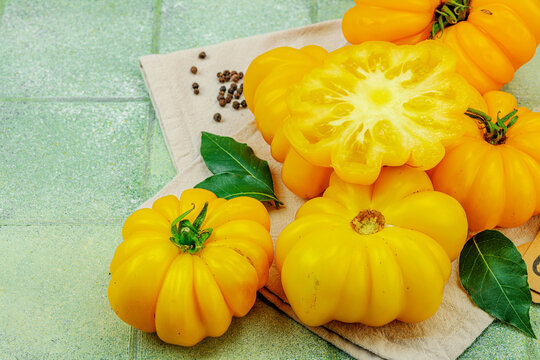 Yellow heirloom beefsteak tomatoes with a cross-section slice, black peppercorns, and paper tag