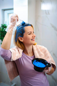 Woman coloring hair blue at home in bathroom