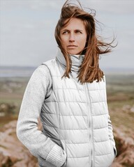 Woman in white puffer vest outdoors in windy landscape © Rawpixel.com
