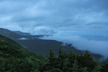 Scenic mountain landscape near Anchorage, Alaska, with green slopes covered in mist and low clouds. Wild northern wilderness and dramatic natural scenery, ideal for travel and outdoor themes. © marinasokolchik