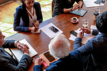 Diverse business team in meeting around table, men and women taking notes