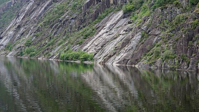 Spiegelung von Felsformationen im Wasser, Fjord am Langfossen Wasserfall in Norwegen