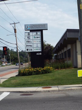 Gatineau, Quebec, Canada &ndash; July 02, 2026: A tall directory sign displaying "various organization logos and the number 408" stands outside the office building on Rue Main.