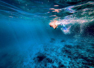 Woman snorkeling underwater in bright blue Mediterranean sea, swimming above a rocky seabed with fins and bubbles, ideal for summer vacation, adventure and travel concepts. © JairoMZ