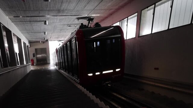 Alpnach, Obwalden, Switzerland - 22 August 2026: View of the red Mount Pilatus cogwheel train arriving at the station platform inside a tunnel.