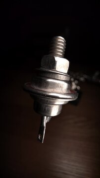 Metal power thyristor electronic component with threaded stud and terminal, close-up.