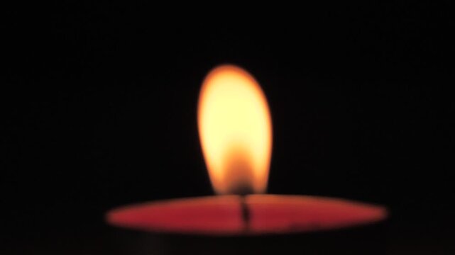 close-up glowing candle flame in darkness slowly defocusing and extinguishing, emphasizing fragility, time, mood transition. meditation themes, emotional endings, dramatic visuals