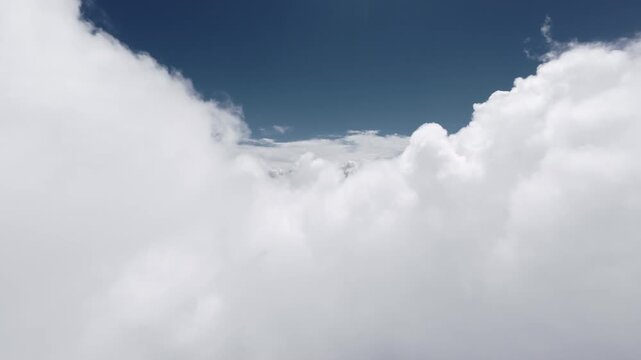 Flying through white cumulus clouds into open blue sky
