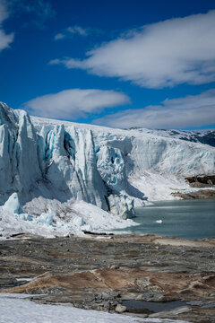 Majestic glacier ice wall meeting glacial lake under blue sky