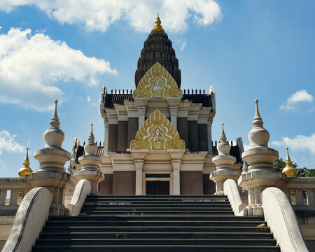 Ornate Khmer-style temple building with golden gables and a stone stairway under a blue sky, Wat Chalong, Phuket, Thailand