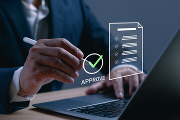 Business document approval concept with a professional signing paperwork beside a laptop, checkmark and verified form representing authorization, compliance, contract review and workflow © PB Studio Photo