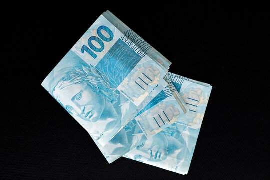 Brazilian hundred real banknotes on a sleek black background