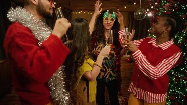 Diverse young friends toasting with champagne flutes and celebrating Christmas near decorated tree. Perfect for New Year advertising, winter holiday promos, and festive party video projects