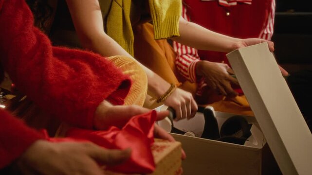 Diverse young adults unboxing VR headset gift during holiday celebration, woman putting virtual reality goggles on friend. Ideal footage for consumer electronics holiday advertising campaigns