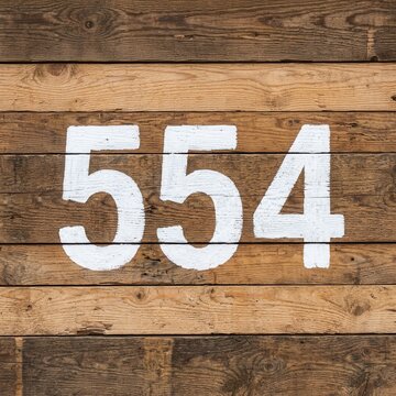 Rustic Wood Panel With Bold White Number Fifty Five Four Displayed Prominently