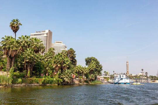 City view of Cairo as seen from the Nile, with tropical gardens and palm trees, high-rise buildings and tower. Cairo is the capital and largest city in Egypt.
