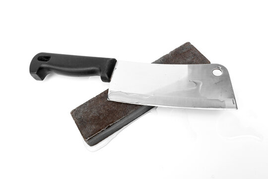 Essential tool for kitchen sharpening and knife care. Meat cleaver knife resting on a wet sharpening whetstone isolated on white background.