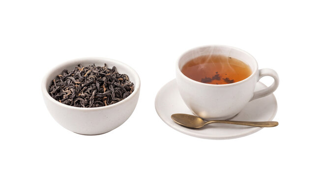 Aromatic black tea in white ceramic cup, bowl of dried loose tea leaves, steaming hot herbal drink on white background