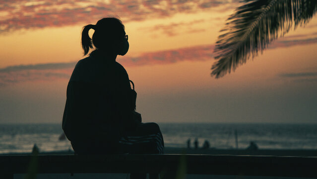 Silhouette of a person sitting alone and watching the sunset over the sea from a tropical beach, Kaohsiung, Taiwan