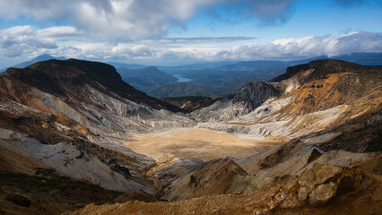 Barren volcanic crater with sulfur-stained rocks and a sandy floor seen from the summit of Mount Adatara, Fukushima, Japan © MasaH