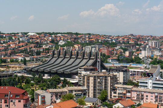 Pristina, Kosovo - 19 June 2025: View of the Cathedral of Saint Mother Teresa surrounded by urban buildings and rooftops under a clear blue sky.