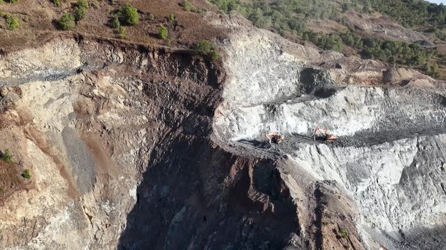 Heavy machinery excavating and digging deep inside a massive open pit coal mine in South Kalimantan