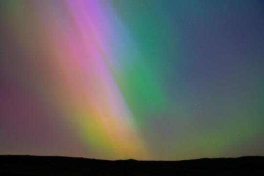 View of the Aurora Borealis illuminating the night sky above the rocky landscape of The Roaches in Leek, England, United Kingdom.