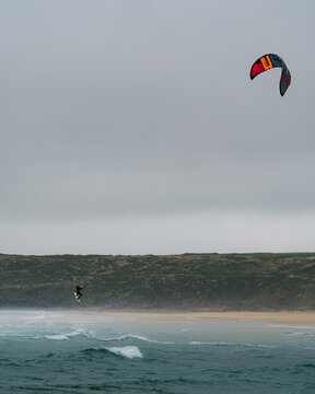 View of a kitesurfer performing a jump over the waves at Freshwater West, Wales, United Kingdom.