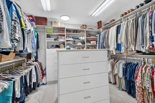 Organized walk-in closet featuring clothing racks shelves drawers and shoe display organization kits