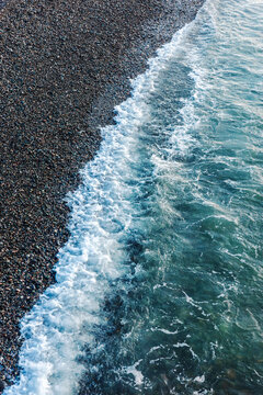 Pebble shoreline surf on coastal beach, erosion, seawater tide, geology, climate resilience, rocky coast dynamics and environmental study background.