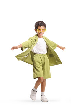 Cheerful little boy in a green suit and yellow glasses spinning