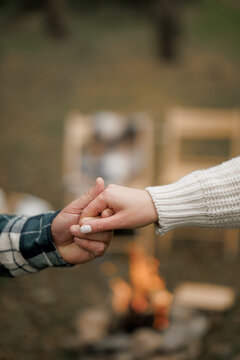 Two hands hold tight by warm fire in quiet forest evening sharing calm peaceful moment together