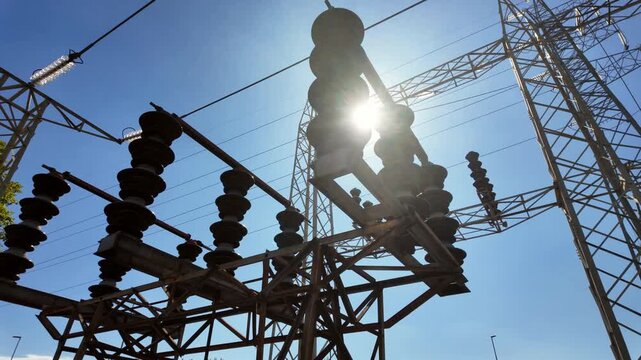 Silhouette of electrical parts and structural elements of a power plant. Lens flare in the camera as the sun appears through the structure due to camera movement