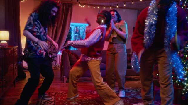 Multiethnic young friends dancing energetically during Christmas home party. Footage suited for holiday seasonal advertising, festive party campaigns, or social gathering promos