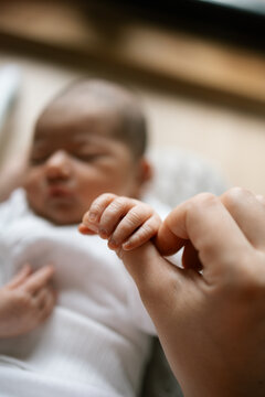 Hand gently holding newborn baby's tiny fingers in quiet moment of care and connection