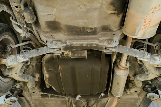Underside view of car reveals mechanic work needed for auto repair in busy shop with focused and serious professional mood