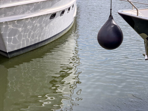 Black Spherical Boat Fender Hanging Between Moored Yachts at Antwerp Marina, Belgium