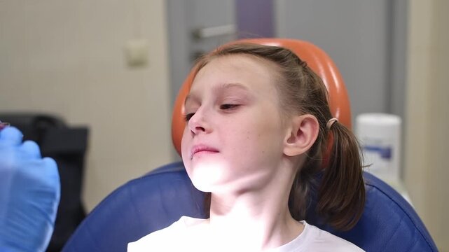 Dentist fits removable orthodontic expansion plate for child during dental appointment and checks fit and comfort in mouth.