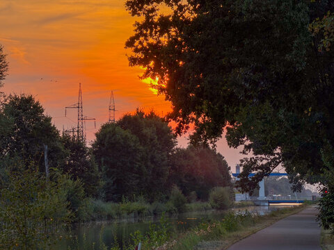 Dramatic Orange Sunset Over Canal Towpath with Power Pylons in Rijkevorsel, Belgium