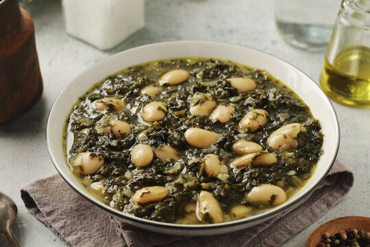 A bowl with traditional Tuscan kale salad and white beans soup Cavolo nero e fagioli	