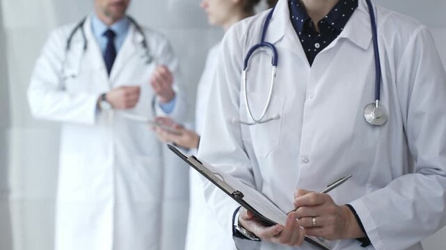Medical professional writing on clipboard with stethoscope, a doctor and female assistant collaborating in a clinic, discussing patient data and healthcare information