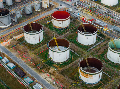 Aerial view of industrial fuel depot with large cylindrical oil storage tanks, metal catwalks, and pipelines in Rome, Lazio, Italy.