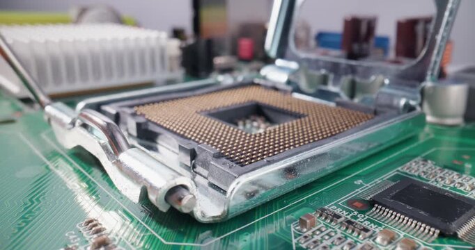 Worker AI chip installation in cpu socket and gold pins across green motherboard with heatsink and electronic components inside electronics lab.