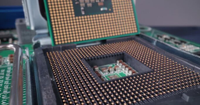 Tracking shot of cpu processor chip being lifted and aligned into motherboard socket on green circuit board close up with slow motion tilt.